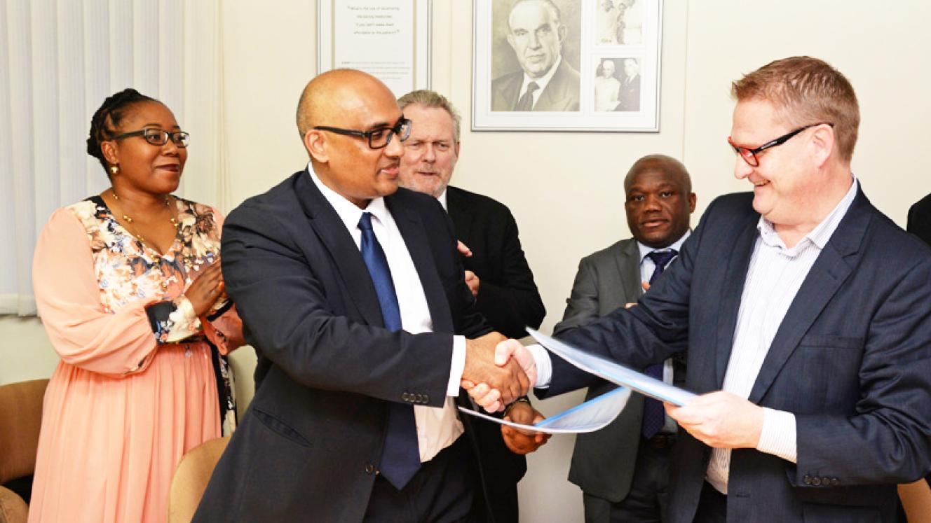 CEO of Dube Trade Port, Hamish Erskine and CEO of Cipla Biotec South Africa, Divian Govender, shake hands after the signing. In the background from left to right is Dr. Bridgette Gasa, chairperson of Dube TradePort Corporation, Rob Davies, Minister of Trade and Industry and Sihle Zikalala, KwaZuluNatal MEC for Economic Development, Tourism, and Environmental Affairs. 
