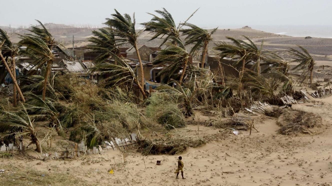 A lone figure strolls past a destroyed settlement in cyclone-devastated Mozambique.