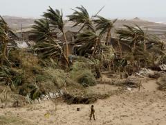A lone figure strolls past a destroyed settlement in cyclone-devastated Mozambique.