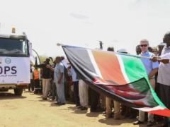 Bystanders wave the Kenyan flag upon arrival at the Port of Mombasa of the first shipment of Kenyan crude.