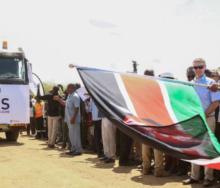 Bystanders wave the Kenyan flag upon arrival at the Port of Mombasa of the first shipment of Kenyan crude.